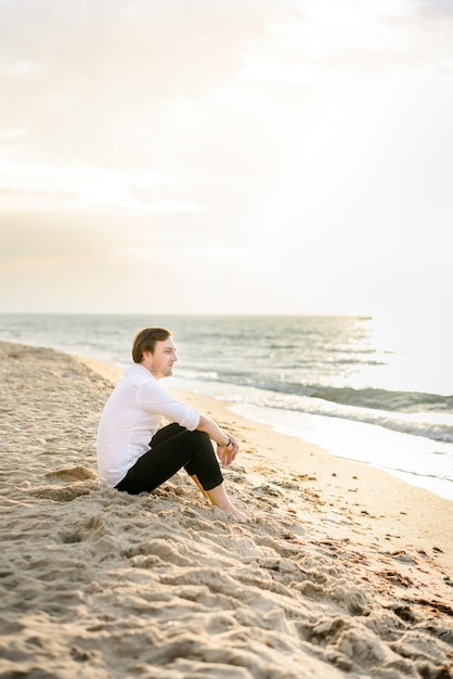 Foto gratuita apuesto novio elegante posando en la playa