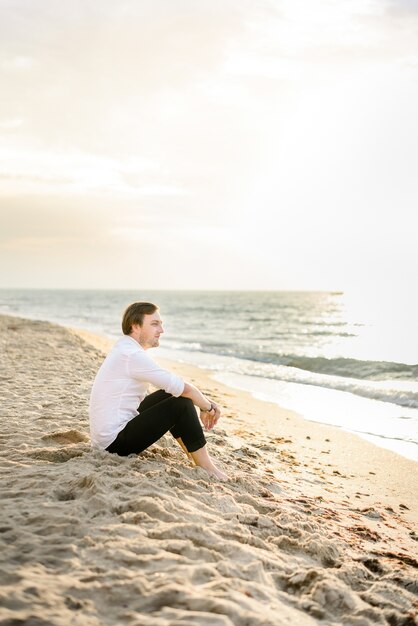 Apuesto novio elegante posando en la playa