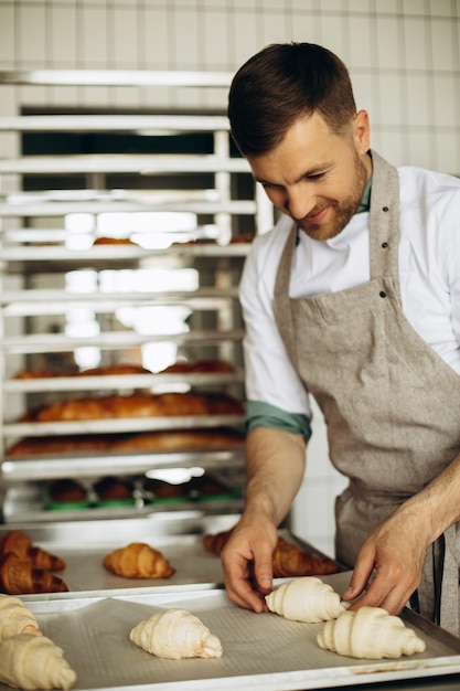 Foto gratuita apuesto panadero preparando croissants en la casa de horneado