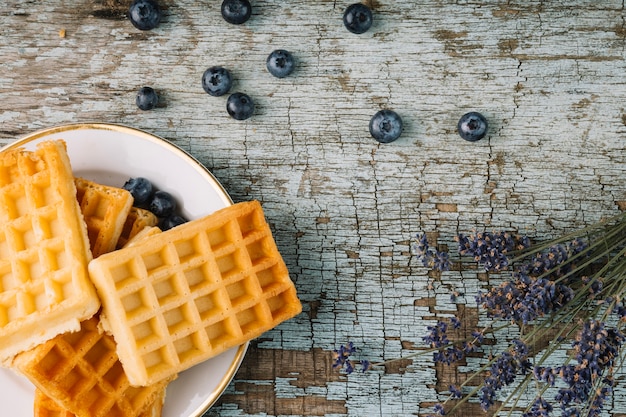 Arándanos cerca de waffles y flores