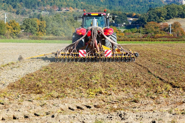 Arando el tractor pesado durante el cultivo agrícola trabaja en el campo con arado