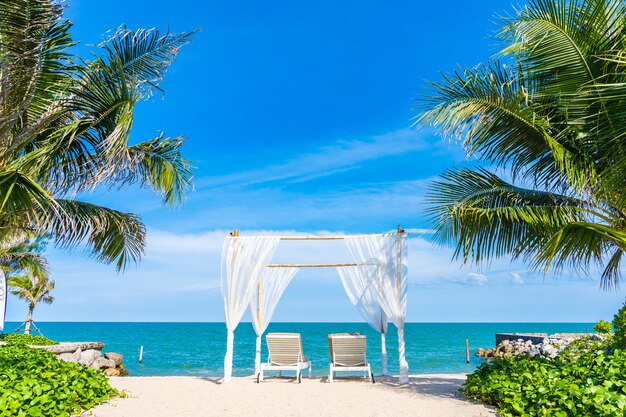 Arco blanco y tumbonas en playa tropical