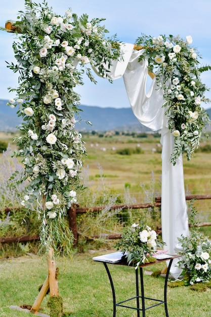 Arco de boda decorado con vegetación y eustomas blancas en los jardines al aire libre