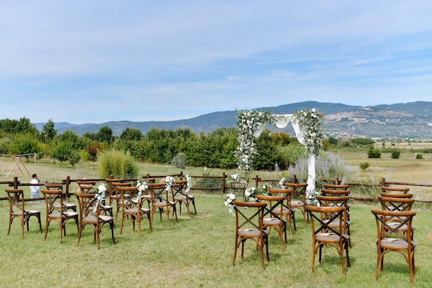 Arco de bodas ceremonial y sillas chiavari para invitados al aire libre