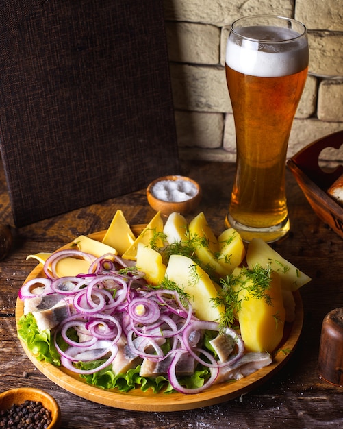 Foto gratuita arenque con cebolla papas, mantequilla y verduras servidas con cerveza