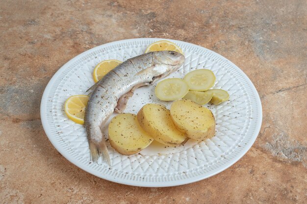 Arenque con patatas hervidas en la placa blanca.