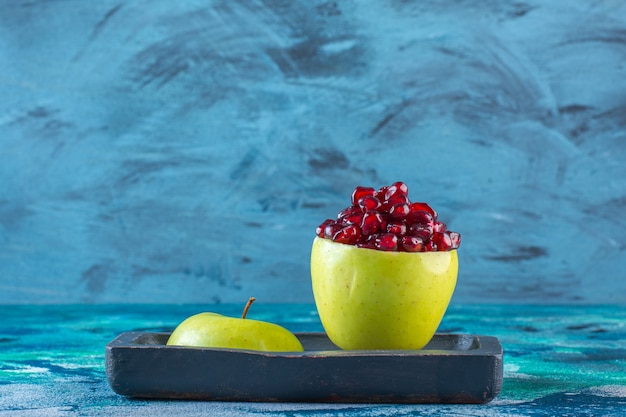 Foto gratuita arilos de manzana y granada en rodajas sobre una placa de madera