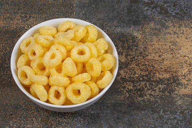 Aros de cereales sabrosos en tazón de fuente blanco.