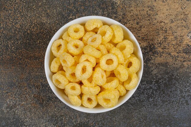 Aros de cereales sabrosos en tazón de fuente blanco.