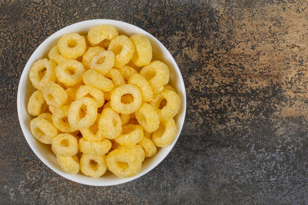 Aros de cereales sabrosos en tazón de fuente blanco.