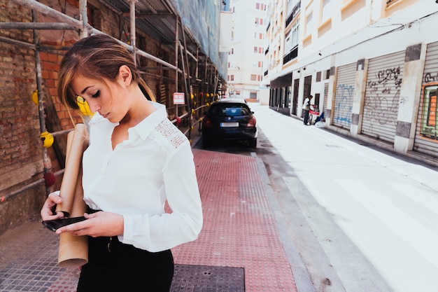 Arquitecta joven con teléfono y planos