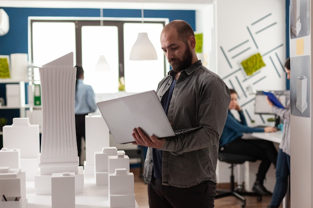 Arquitecto adulto urbano inspeccionando el plan de diseño en el lugar de trabajo