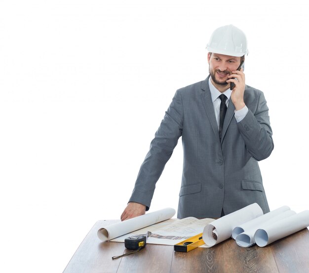 Arquitecto confidente leyendo el plan de arquitectura del edificio, de pie en el lugar de trabajo, cerca de la mesa