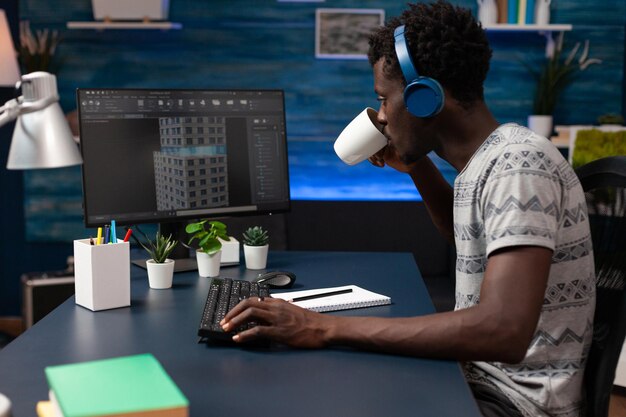 Arquitecto desarrollador usando auriculares mirando el boceto del edificio analizando el prototipo en la computadora trabajando a distancia desde casa en el proyecto inmobiliario. Ingeniero empresario desarrollando estructura arquitectónica