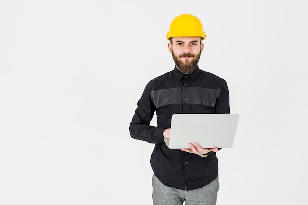 Arquitecto joven, llevando, hardhat amarillo, tenencia, portátil, computadora portátil