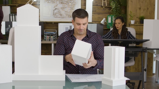 Arquitecto masculino mirando un modelo impreso en 3D de un edificio de oficinas de negocios real