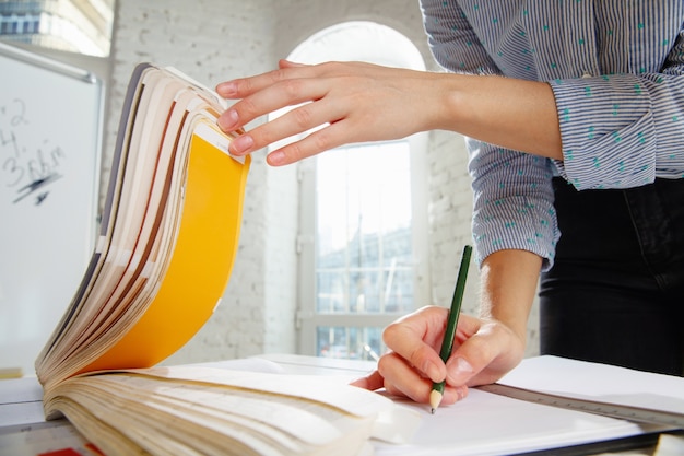 Foto gratuita arquitecto o diseñador de interiores profesional que trabaja con paleta de colores, dibujos de habitaciones en oficinas modernas. modelo de mujer joven que planifica el futuro piso o casa, eligiendo colores y desviación.