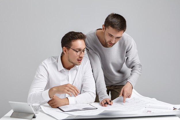 Los arquitectos creativos desarrollan el plan de la casa, miran con atención los planos, estudian los dibujos,