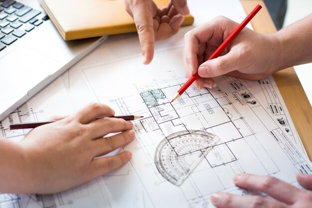 Arquitectos discutir en la mesa con el proyecto - Closeup en las manos y el proyecto de impresión.