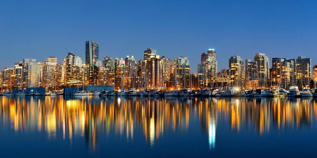 Arquitectura del centro de Vancouver y barco con reflejos en el agua al atardecer panorama