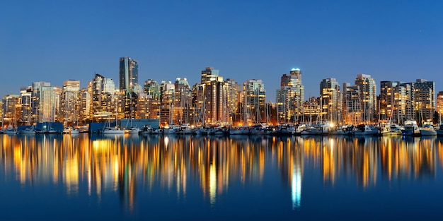 Arquitectura del centro de Vancouver y barco con reflejos en el agua al atardecer panorama