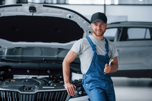 Arreglaremos cualquier cosa. Empleado en el uniforme de color azul se encuentra en el salón del automóvil