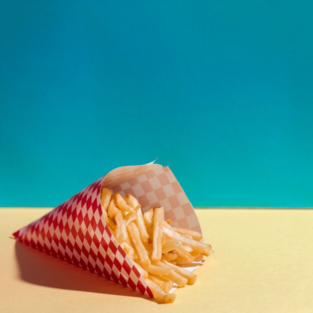 Arreglo de alto ángulo con deliciosas papas fritas en mesa amarilla