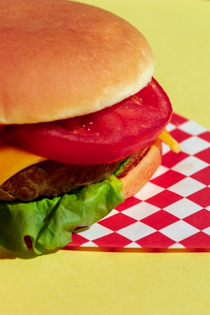 Foto gratuita arreglo de alto ángulo con media hamburguesa con queso y fondo amarillo