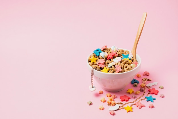Arreglo de ángulo alto con tazón de cereal y fondo rosa