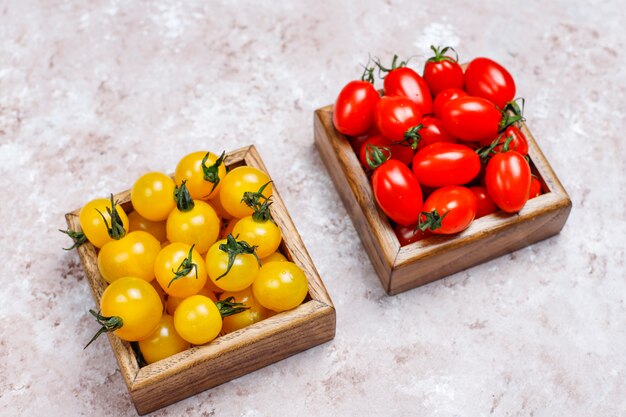 Arreglo de coloridos tomates frescos surtidos en superficie de concreto