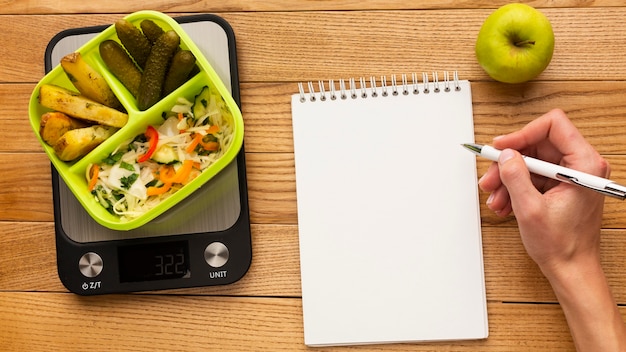 Arreglo de comida sabrosa vista superior con cuaderno vacío