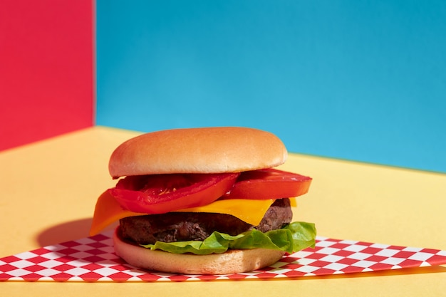 Foto gratuita arreglo con una deliciosa hamburguesa con queso en la mesa amarilla