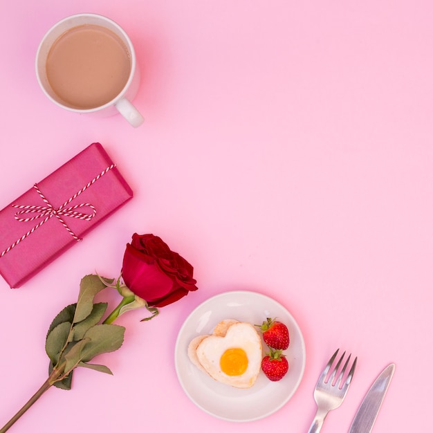 Arreglo de desayuno romántico con rosa y presente.