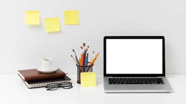 Arreglo de elementos de escritorio con laptop de pantalla vacía