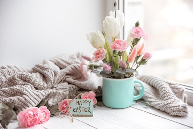 Arreglo floral de Pascua con flores naturales y la inscripción Feliz Pascua en la tarjeta.