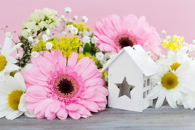 Arreglo con flores y casa de madera.