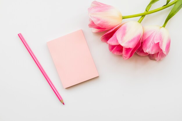 Arreglo de flores y cuaderno con lapiz.