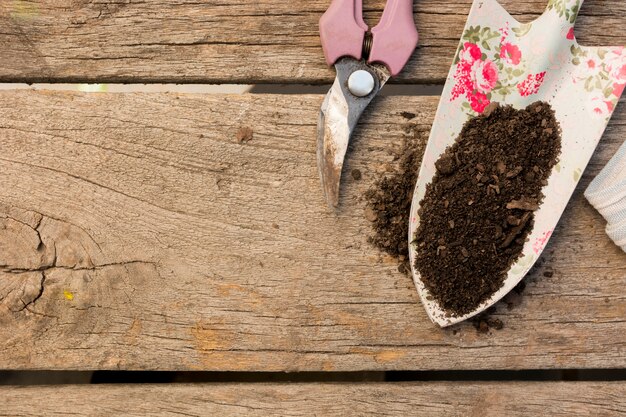 Arreglo de herramientas de jardinería sobre fondo de madera con espacio de copia