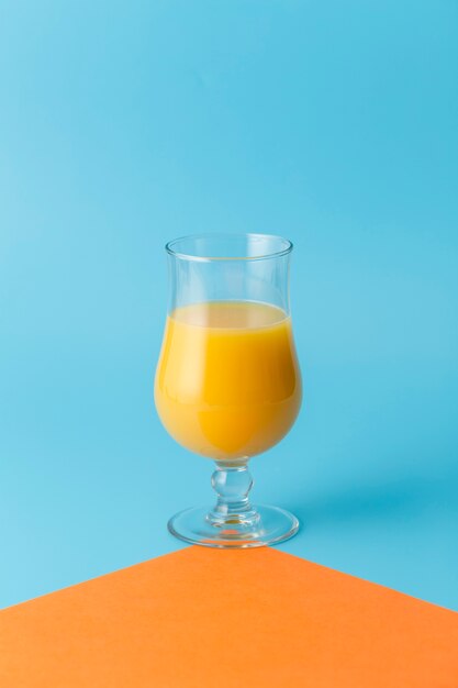 Arreglo con jugo de naranja y fondo azul.