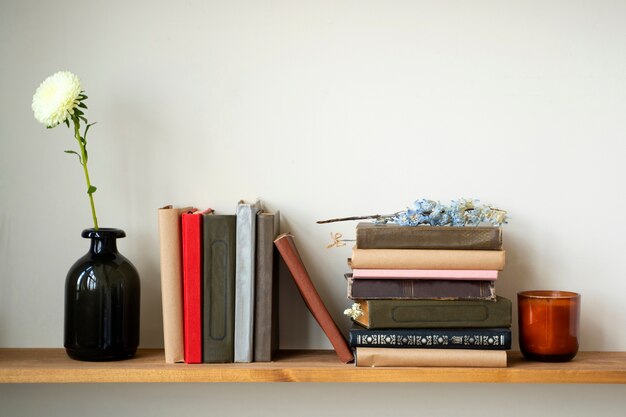 Arreglo de libros en estante con flor azul.