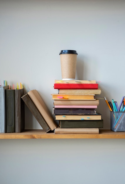 Foto gratuita arreglo de libros en estante con taza de café.