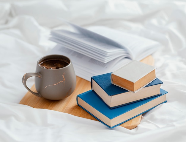 Arreglo con libros y taza en la cama.