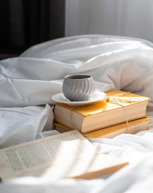 Arreglo con libros y taza en la cama.