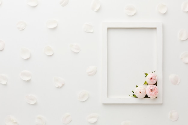 Arreglo de marco blanco vacío con rosas y pétalos