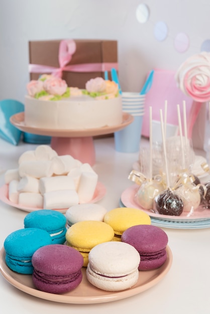 Arreglo de mesa para evento de cumpleaños con pastel y macarons.