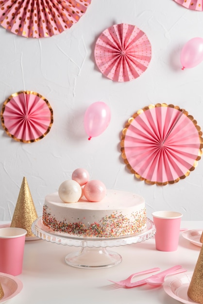 Arreglo de mesa para evento de cumpleaños con pastel y sombreros de cumpleaños.