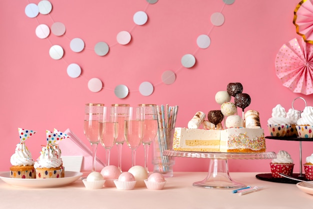 Arreglo de mesa para evento de cumpleaños con torta y copas de champagne