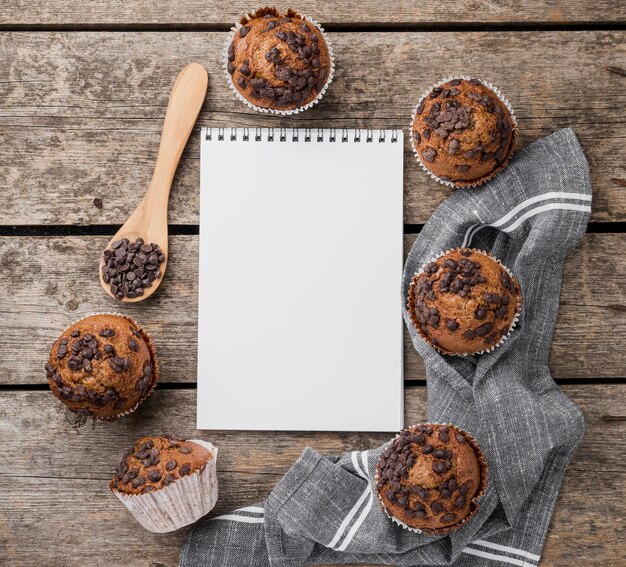 Foto gratuita arreglo de muffins horneados y libreta vacía