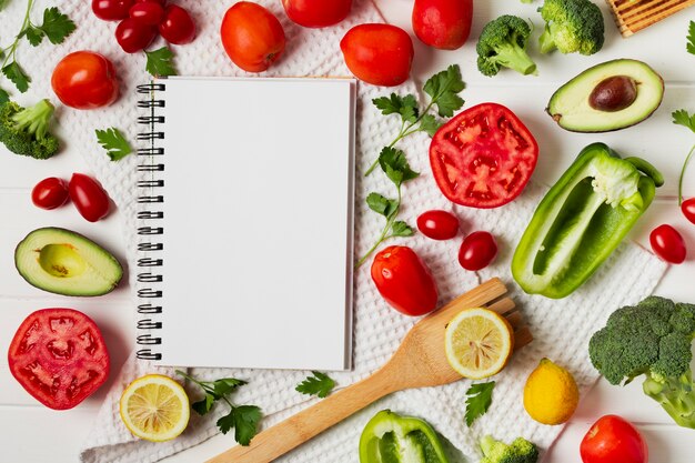 Arreglo plano con verduras y cuaderno