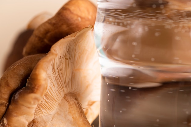 Foto gratuita arreglo de primer plano con champiñones y vaso de agua